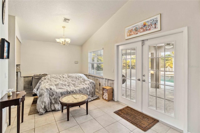 tiled bedroom with vaulted ceiling, access to outside, a notable chandelier, a textured ceiling, and french doors