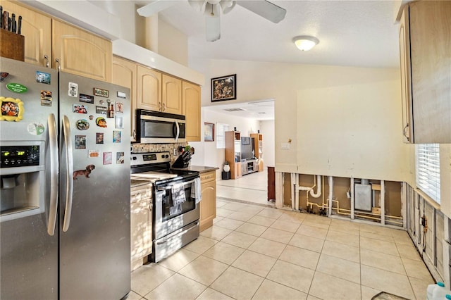 kitchen with vaulted ceiling, light tile patterned flooring, appliances with stainless steel finishes, light brown cabinetry, and ceiling fan