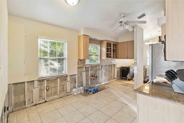 kitchen featuring light tile patterned floors, decorative backsplash, a textured ceiling, and light brown cabinets