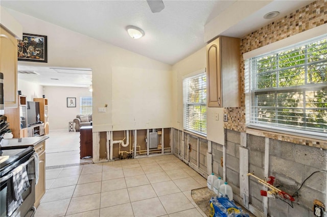 kitchen with vaulted ceiling, light tile patterned floors, ceiling fan, and stainless steel electric range