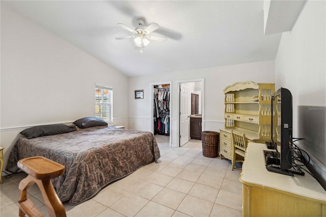 tiled bedroom featuring lofted ceiling, ensuite bathroom, a walk in closet, a closet, and ceiling fan