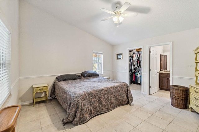 bedroom with lofted ceiling, light tile patterned floors, ensuite bathroom, a walk in closet, and a closet