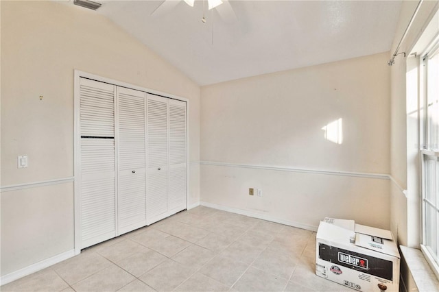 unfurnished bedroom featuring lofted ceiling, light tile patterned floors, ceiling fan, heating unit, and a closet