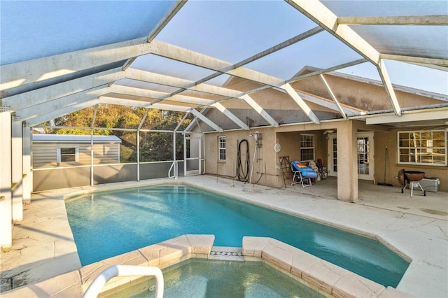 view of swimming pool with a storage shed, a patio area, and glass enclosure