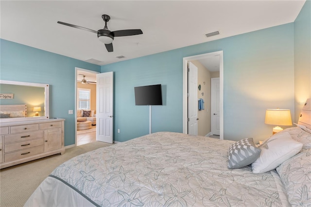 bedroom featuring ensuite bath, light colored carpet, and ceiling fan