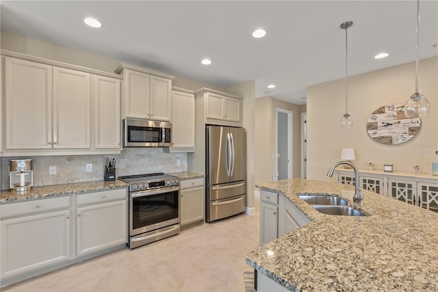 kitchen with sink, stainless steel appliances, light stone counters, tasteful backsplash, and decorative light fixtures