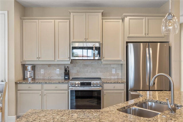 kitchen featuring sink, backsplash, light stone countertops, and appliances with stainless steel finishes