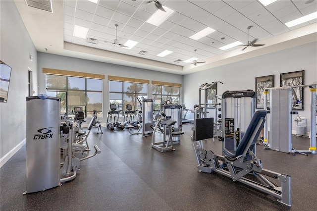 gym with a towering ceiling, a drop ceiling, and ceiling fan