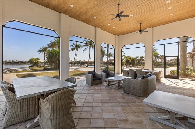 sunroom featuring wood ceiling, ceiling fan, and a water view