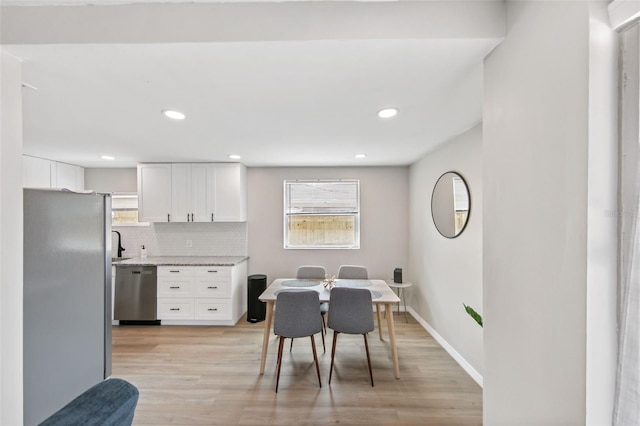 dining room with plenty of natural light, sink, and light hardwood / wood-style flooring