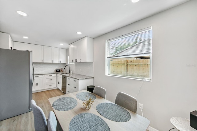 kitchen featuring sink, light hardwood / wood-style flooring, stainless steel appliances, decorative backsplash, and white cabinets