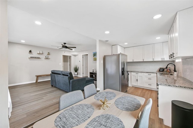 dining room featuring ceiling fan, sink, and light wood-type flooring