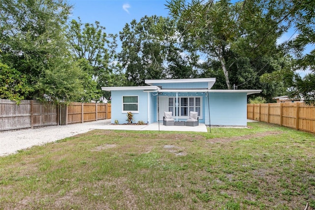 rear view of property featuring a patio and a lawn