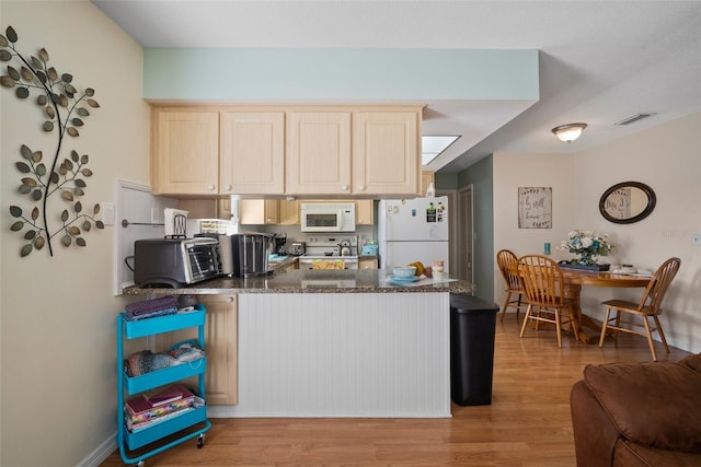 kitchen featuring dark stone countertops, light brown cabinetry, white appliances, and light hardwood / wood-style floors