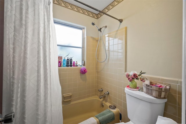 bathroom with tile walls, shower / bathtub combination with curtain, and toilet