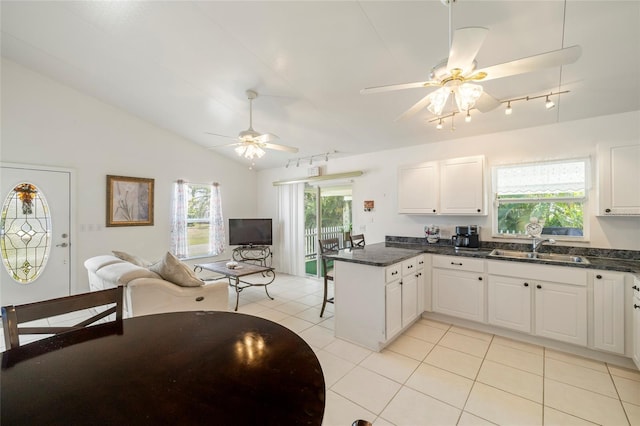 kitchen with vaulted ceiling, kitchen peninsula, sink, and white cabinets