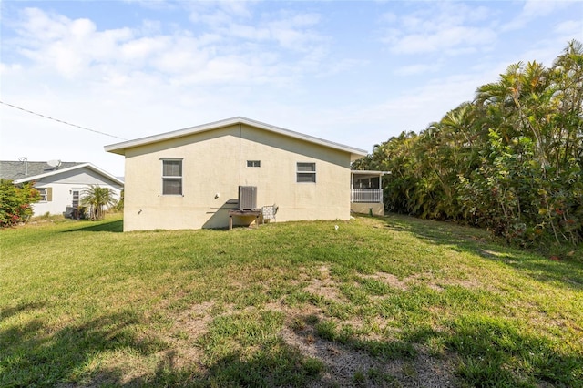 back of property with central AC unit, a sunroom, and a lawn