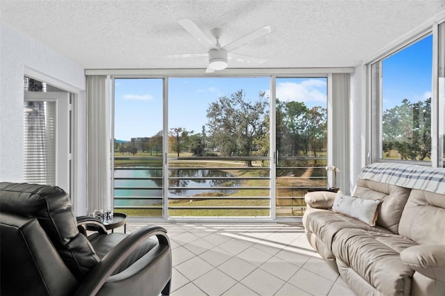 sunroom with plenty of natural light, ceiling fan, and a water view