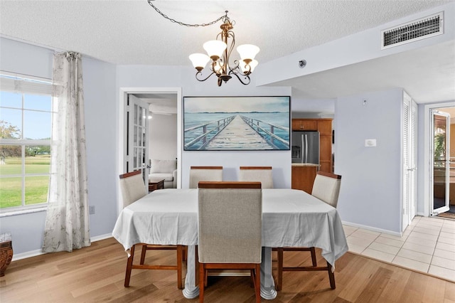 dining room featuring an inviting chandelier, light hardwood / wood-style floors, and a textured ceiling