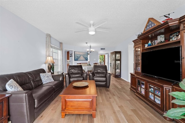 living room featuring plenty of natural light, light wood-type flooring, and an inviting chandelier