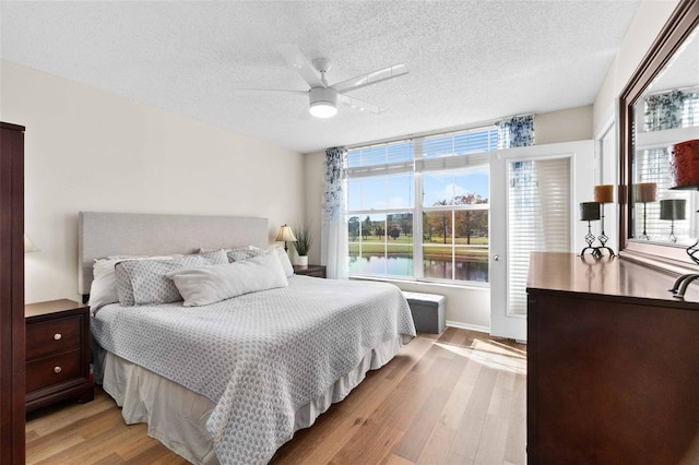 bedroom with multiple windows, ceiling fan, a textured ceiling, and light hardwood / wood-style flooring