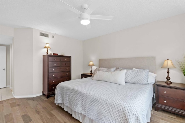 bedroom with ceiling fan, a textured ceiling, and light wood-type flooring