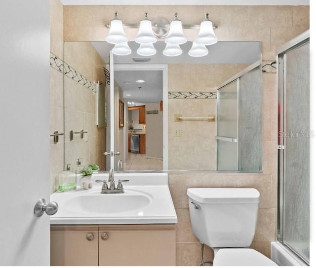 full bathroom with vanity, tile walls, shower / bath combination with glass door, and toilet