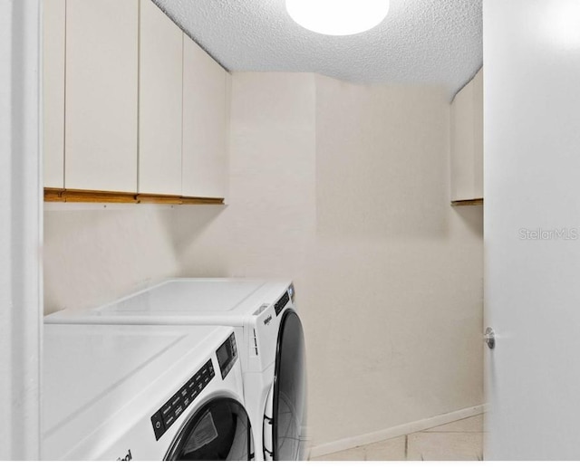 laundry room with cabinets, washing machine and clothes dryer, a textured ceiling, and light tile patterned floors