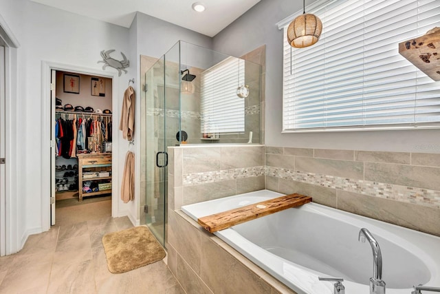 full bath featuring a spacious closet, a stall shower, and a bath