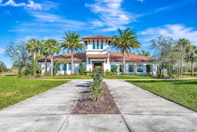 view of front facade featuring driveway, stucco siding, a tiled roof, and a front yard