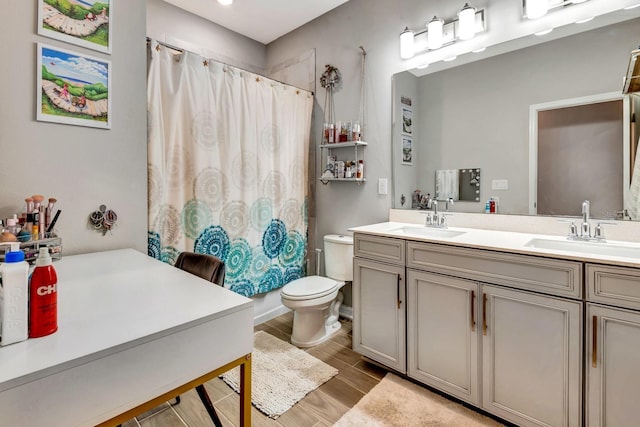 bathroom with double vanity, toilet, a sink, and wood finish floors