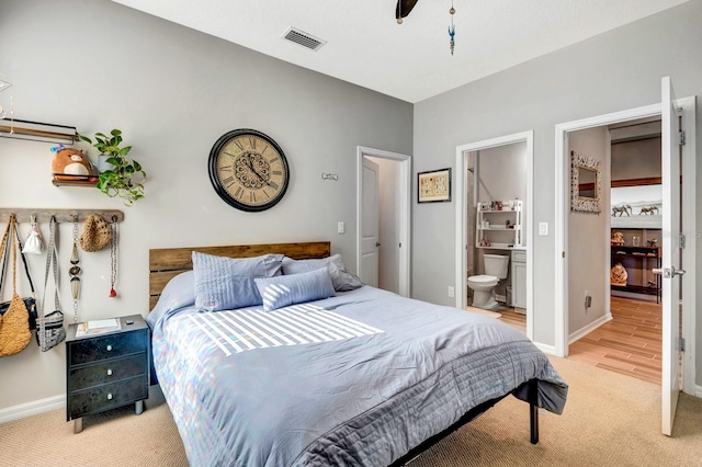 bedroom with baseboards, visible vents, light colored carpet, ceiling fan, and ensuite bathroom