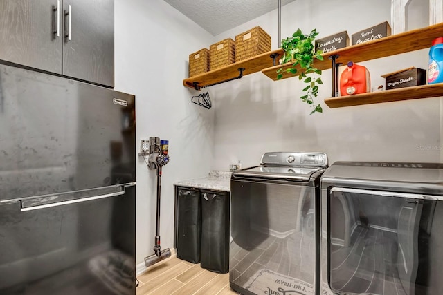 washroom featuring washing machine and dryer, laundry area, a textured ceiling, and wood tiled floor