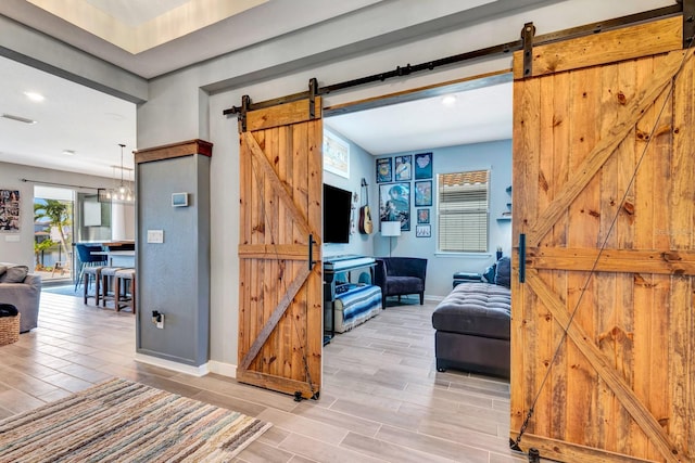 interior space featuring a barn door, visible vents, baseboards, and wood finish floors