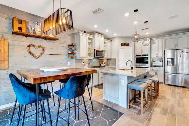 kitchen with visible vents, glass insert cabinets, appliances with stainless steel finishes, pendant lighting, and a sink