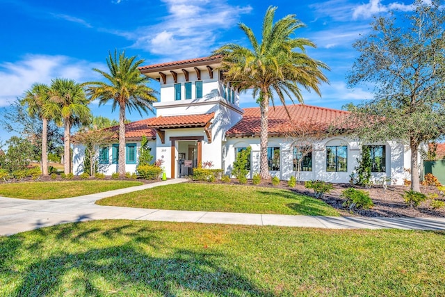 mediterranean / spanish house with a front yard, a tile roof, and stucco siding