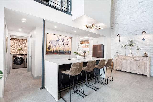 kitchen featuring freestanding refrigerator, a breakfast bar, white cabinetry, and light stone counters