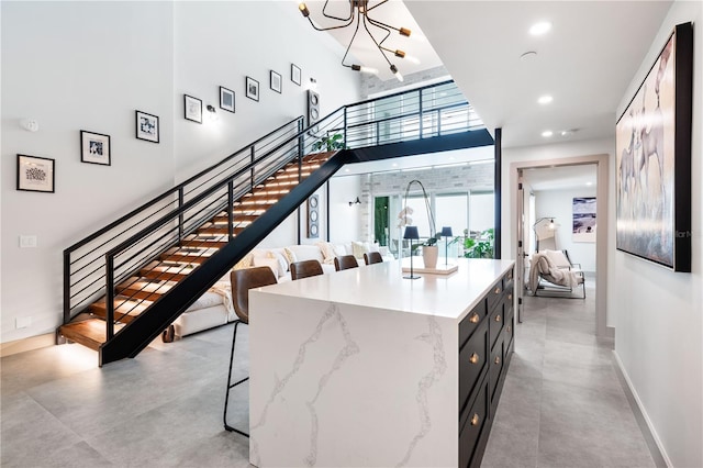 interior space with recessed lighting, a towering ceiling, baseboards, stairway, and an inviting chandelier