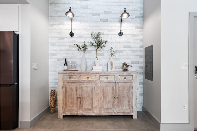 bar with brick wall, electric panel, refrigerator, and dark tile patterned flooring