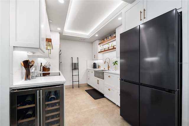 kitchen featuring wine cooler, white cabinetry, sink, and black appliances