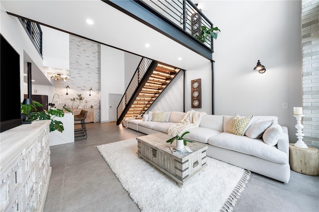 living room featuring concrete flooring, recessed lighting, stairway, and a high ceiling