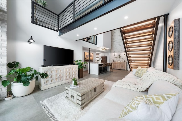 living area with recessed lighting, a towering ceiling, and finished concrete floors