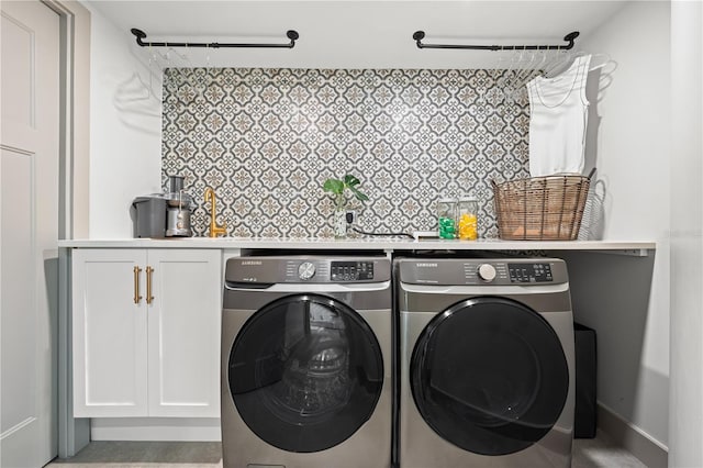 clothes washing area with cabinets and washing machine and clothes dryer