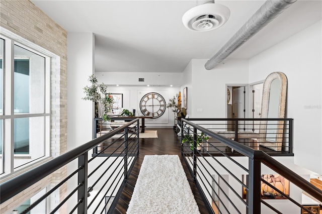 hallway featuring a wealth of natural light, dark wood-type flooring, visible vents, and an upstairs landing