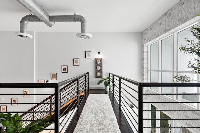 hallway featuring dark hardwood / wood-style flooring and brick wall