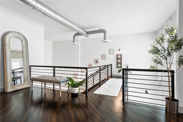 hall with dark wood-style flooring and an upstairs landing