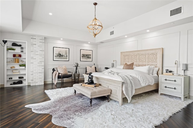 bedroom featuring dark wood-style floors, a notable chandelier, visible vents, and a decorative wall