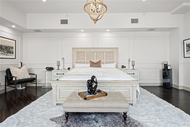 bedroom featuring dark wood finished floors, visible vents, a decorative wall, and a notable chandelier