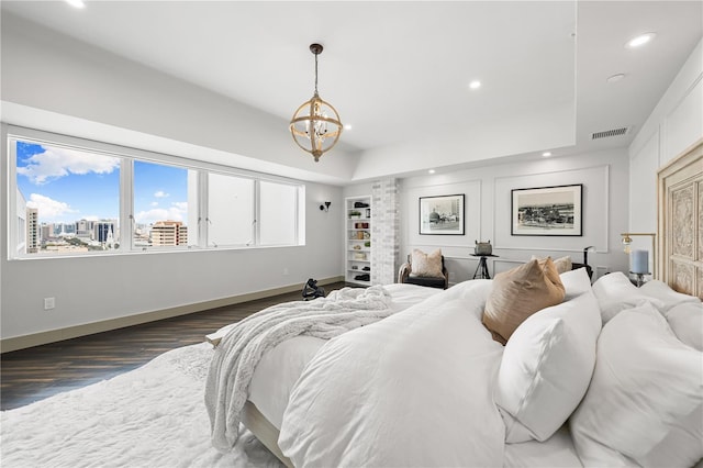 bedroom featuring an inviting chandelier, a tray ceiling, and dark wood-type flooring