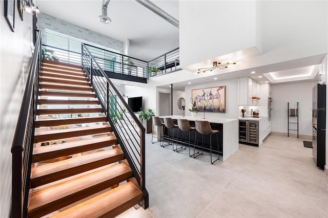 stairway with recessed lighting, indoor wet bar, and a high ceiling